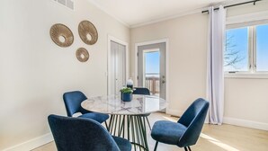 A dining area with a round table, four blue chairs, and a potted plant.