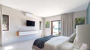 A modern bedroom with a large bed, a mounted TV, and a window with a view of the sea. - VILLA KUXTAL, OCEANFRONT (San Crisanto)