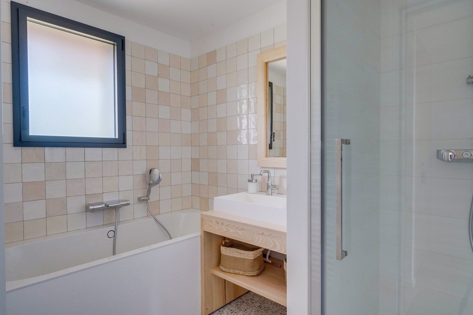 A modern bathroom with a bathtub, a sink with a mirror, and a shower area.