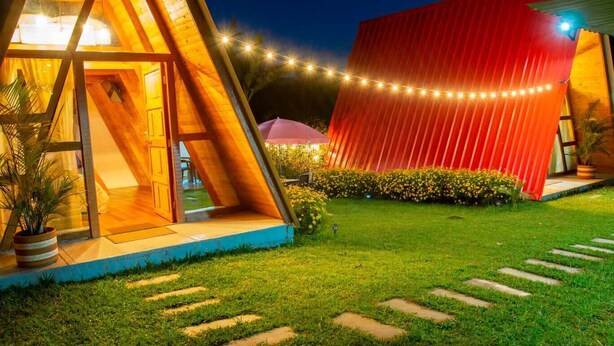 A modern house with a sloped roof, a red exterior wall, and a well-lit entrance. - Cabañas Alpina  (San Agustin)