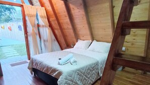 A wooden cabin room with a bed, a ladder, and a view of the outdoors. - Cabañas Alpina  (San Agustin)