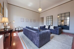 Een moderne woonkamer met een modulaire bank, een bijzettafeltje met een lamp en ingelijste foto's aan de muur.