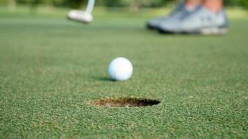 Ein Golfball auf einem Grün, in der Nähe ein Loch.