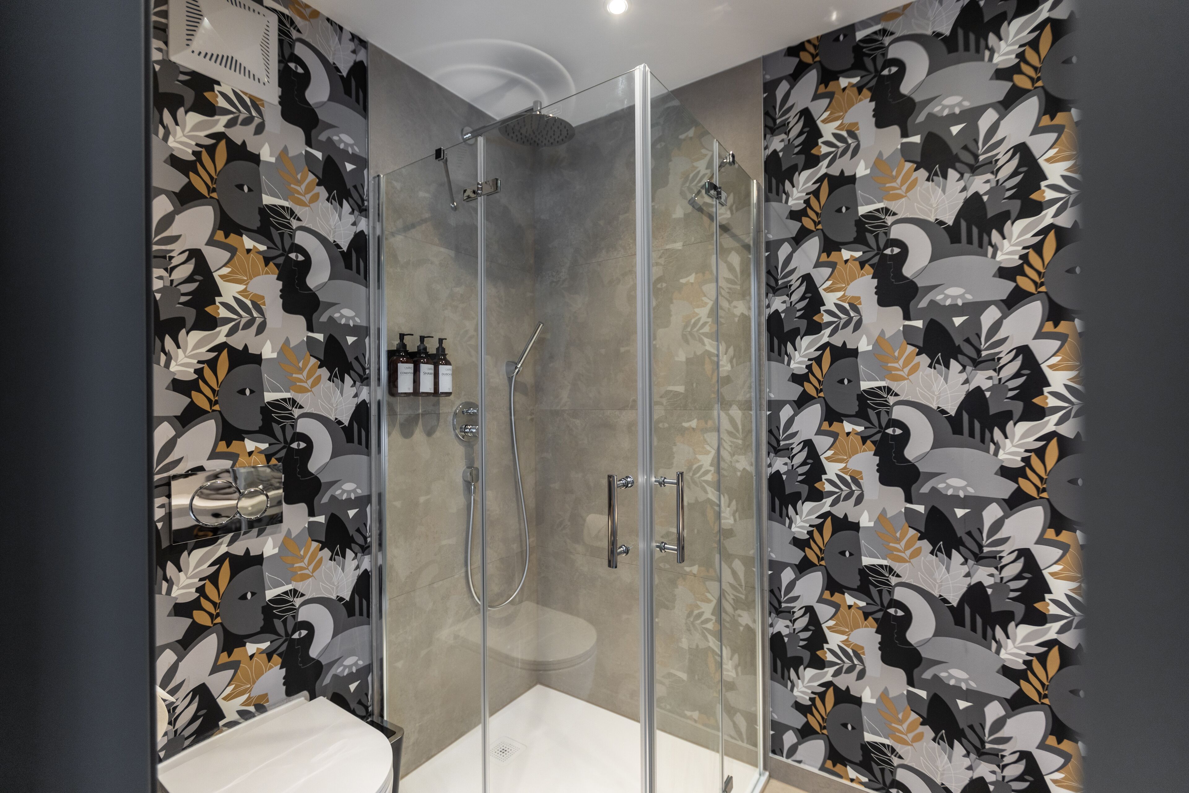 Un baño moderno con ducha acristalada, inodoro y lavamanos.