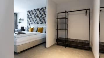 A modern bedroom with a bed, a black metal shelf unit, and a patterned wall.