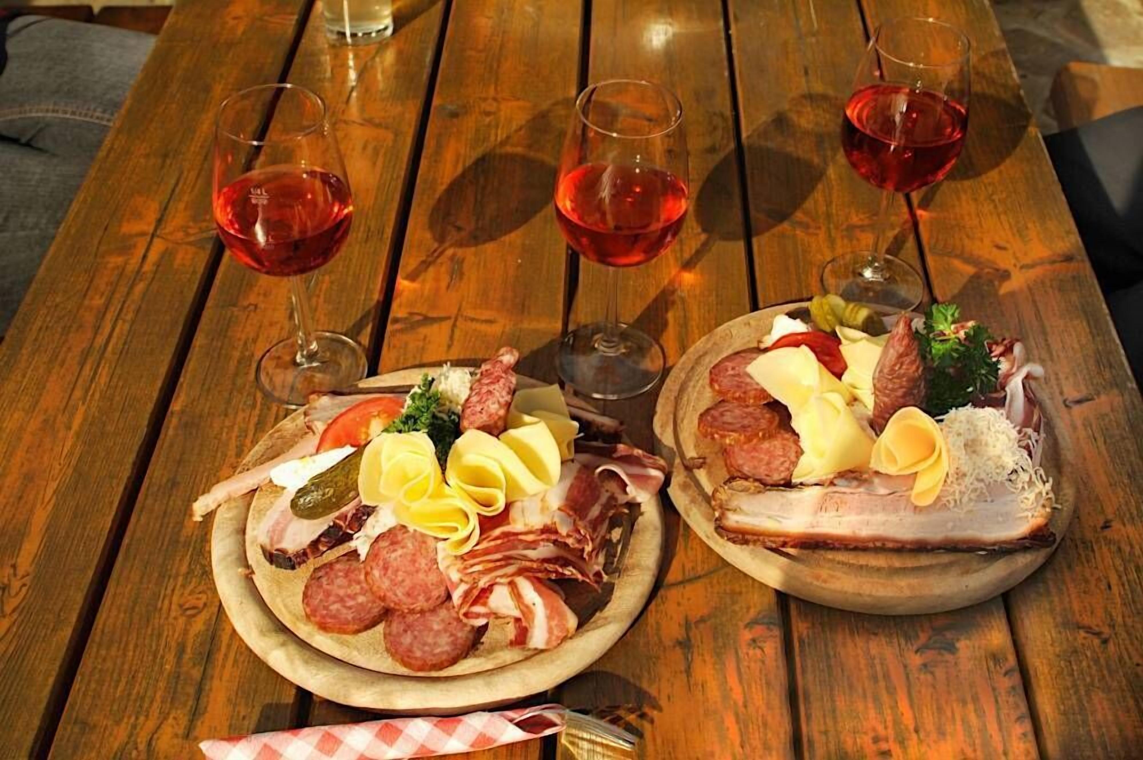 A wooden table with two charcuterie boards and three glasses of red wine.