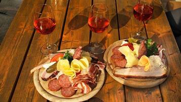 A wooden table with two charcuterie boards and three glasses of red wine.