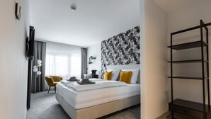 Una habitación de hotel moderna con una cama grande, un escritorio, una silla y un armario.