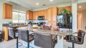 A modern kitchen with granite countertops, wooden cabinets, and stainless steel appliances. - 2 Mi to Coachella: Indio Home w/ Outdoor Oasis (Indio)
