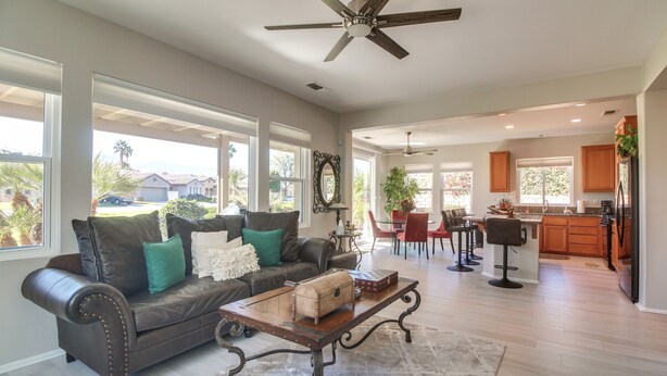 A spacious living room with a leather sofa, a wooden coffee table, and a ceiling fan. - 2 Mi to Coachella: Indio Home w/ Outdoor Oasis (Indio)