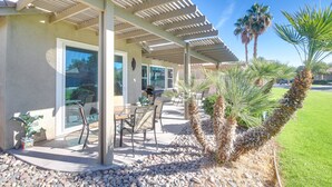 An outdoor patio with a pergola, seating, and palm trees. - 2 Mi to Coachella: Indio Home w/ Outdoor Oasis (Indio)