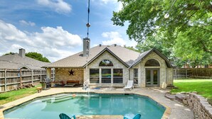 Un jardin avec une piscine, un espace barbecue et une terrasse couverte.