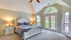 Une chambre à coucher avec un lit, des tables de chevet et un ventilateur de plafond.