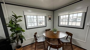 Une salle de conférence avec une table ronde, quatre chaises, une plante en pot et des fenêtres équipées de stores.