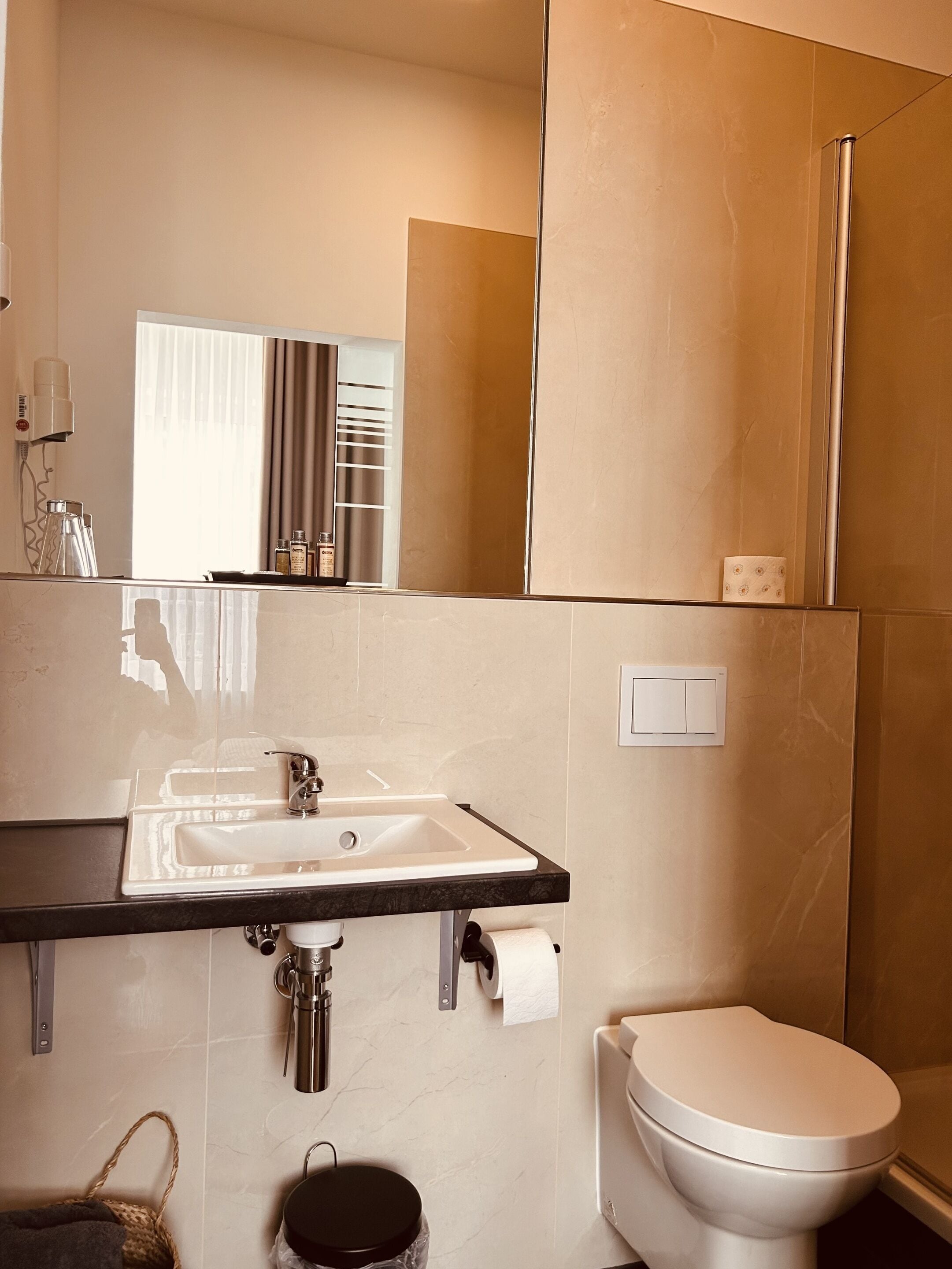 Een moderne badkamer met een wastafel, toilet en douche.