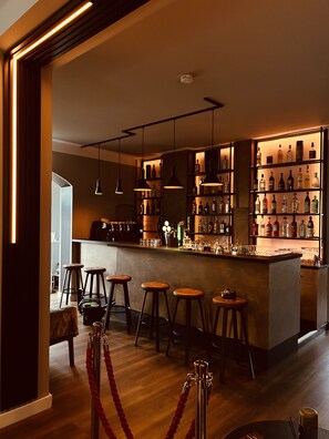 Eine Bar mit Hockern, einer Theke und Regalen voller Flaschen.