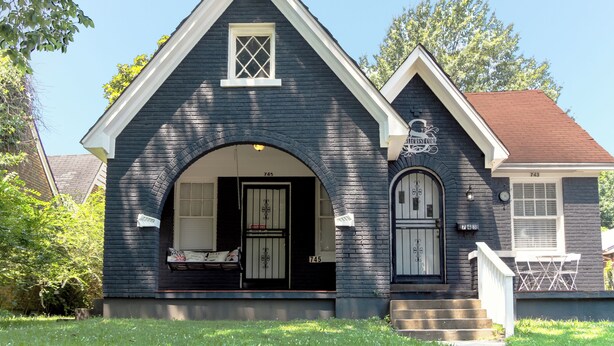 A two-story house with a dark blue exterior, a front porch, and a small attached garage. - Midtown Tiger Retreat with ShellCrestCorp" 745 (Memphis)
