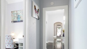 A hallway with a white desk, a patterned chair, and artwork on the walls. - Midtown Tiger Retreat with ShellCrestCorp" 745 (Memphis)