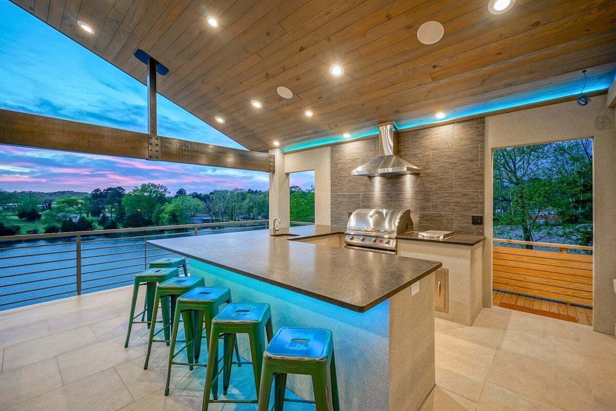 A modern kitchen with a large island, bar stools, and a view of a body of water.