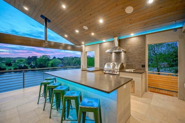 A modern kitchen with a large island, bar stools, and a view of a body of water.