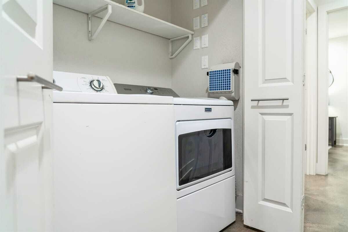 A laundry room with a washer and dryer, a white door, and a blue vent.