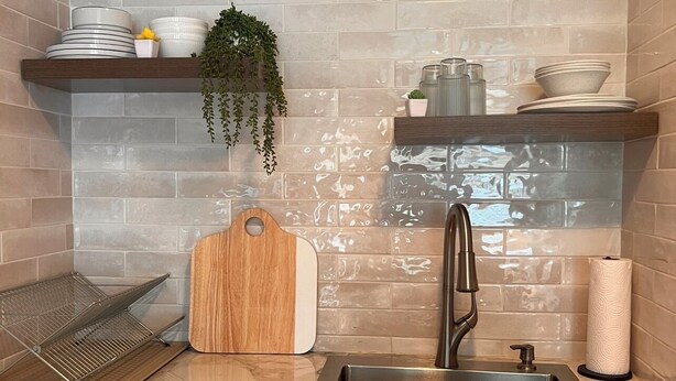 Eine moderne Küche mit Marmorarbeitsplatte, einer Edelstahlspüle und einem Holztisch.