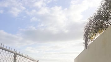 Une personne se tient près d’une porte, avec une vue sur la plage, et tient une serviette à la main.