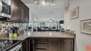 A modern kitchen with dark cabinetry, granite countertops, and a built-in oven.