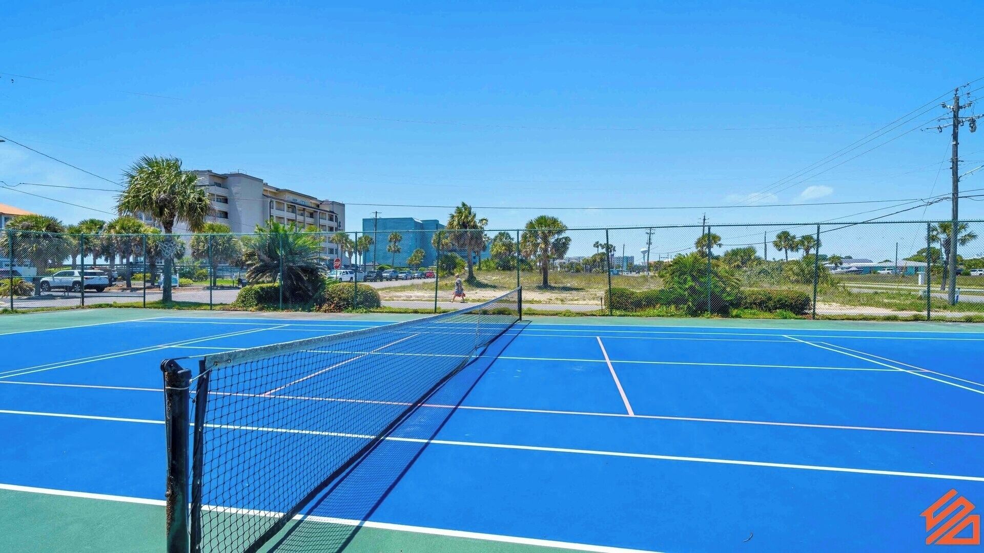 Ein Tennisplatz im Freien mit Netz in der Mitte, umgeben von einem Zaun.