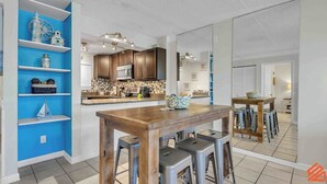 A modern kitchen with wooden cabinets, a central island, and bar stools.
