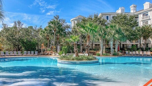 A swimming pool surrounded by palm trees and a building with a classical architectural style. - The Grand in SanDestin Resort Luxury 1BR Condo (Miramar Beach)