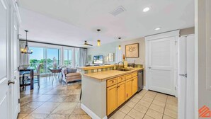 A spacious kitchen with a large island, a dining area with a view, and a separate living space with a balcony. - The Grand in SanDestin Resort Luxury 1BR Condo (Miramar Beach)