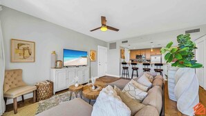 A living room with a sofa, a television, and a ceiling fan. - The Grand in SanDestin Resort Luxury 1BR Condo (Miramar Beach)