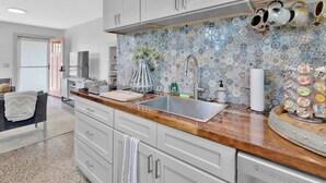 Cocina moderna con gabinetes grises, encimera de madera y salpicadero estampado.