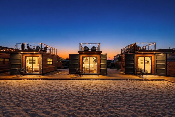 Three wooden cabins with glass doors, each with a balcony and outdoor seating.