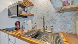 Een moderne keuken met een backsplash in een herringbone patroon, houten aanrecht, een roestvrijstalen spoelbak en ingebouwde planken.