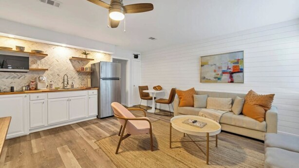 Een moderne keuken met witte kasten, een roestvrijstalen koelkast en een houten eettafel met stoelen.