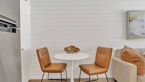 Een moderne keuken met twee leren stoelen, een witte tafel en een beige bank.