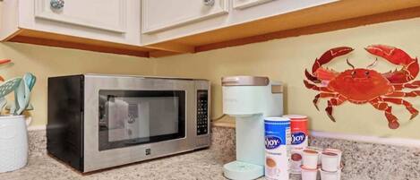 A kitchen with a microwave, a coffee maker, and various kitchen items on the counter.