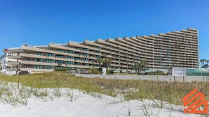 Un hotel grande y de varios pisos con un diseño arquitectónico moderno, con balcones y vistas a la playa.