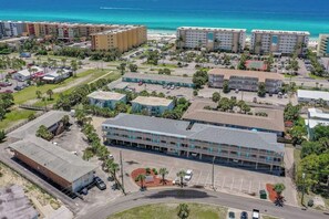 Vista aérea de un complejo hotelero con varias edificaciones, zonas de estacionamiento y una playa al fondo.