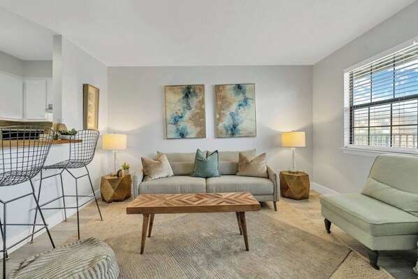A modern living room with a sofa, two side tables, a coffee table, and a chair.