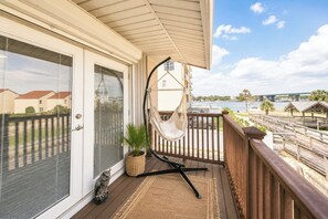 Een balkon met een hangstoel, een bloempot en uitzicht op een waterpartij en gebouwen.