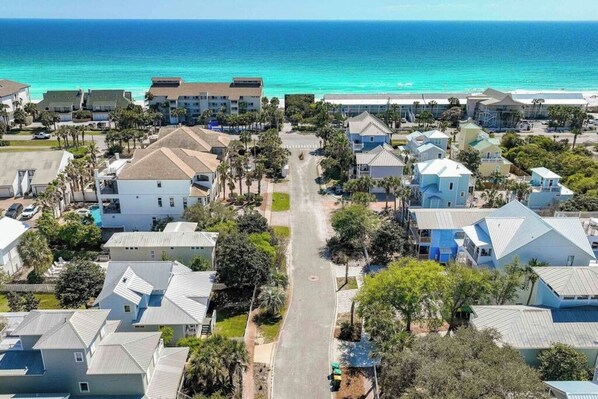 Zona residencial costera con casas, una carretera y una playa al fondo.