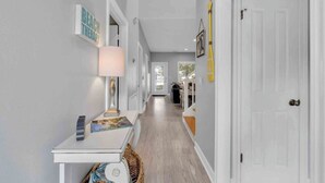 A hallway with a white door, a lamp, and a small table with a magazine. - Large 3BR Family Destin Beach House w Beach Access (Destin)