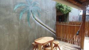 A wooden table and chairs set against a wall with a palm tree mural. - Chalé Palhano Beach Milagres (São Miguel dos Milagres)