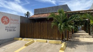 A gated entrance with a palm tree and a wooden fence. - Chalé Palhano Beach Milagres (São Miguel dos Milagres)