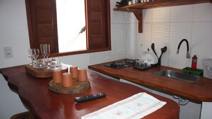 A kitchen with a wooden countertop, a sink, and a window with wooden shutters. - Chalé Palhano Beach Milagres (São Miguel dos Milagres)