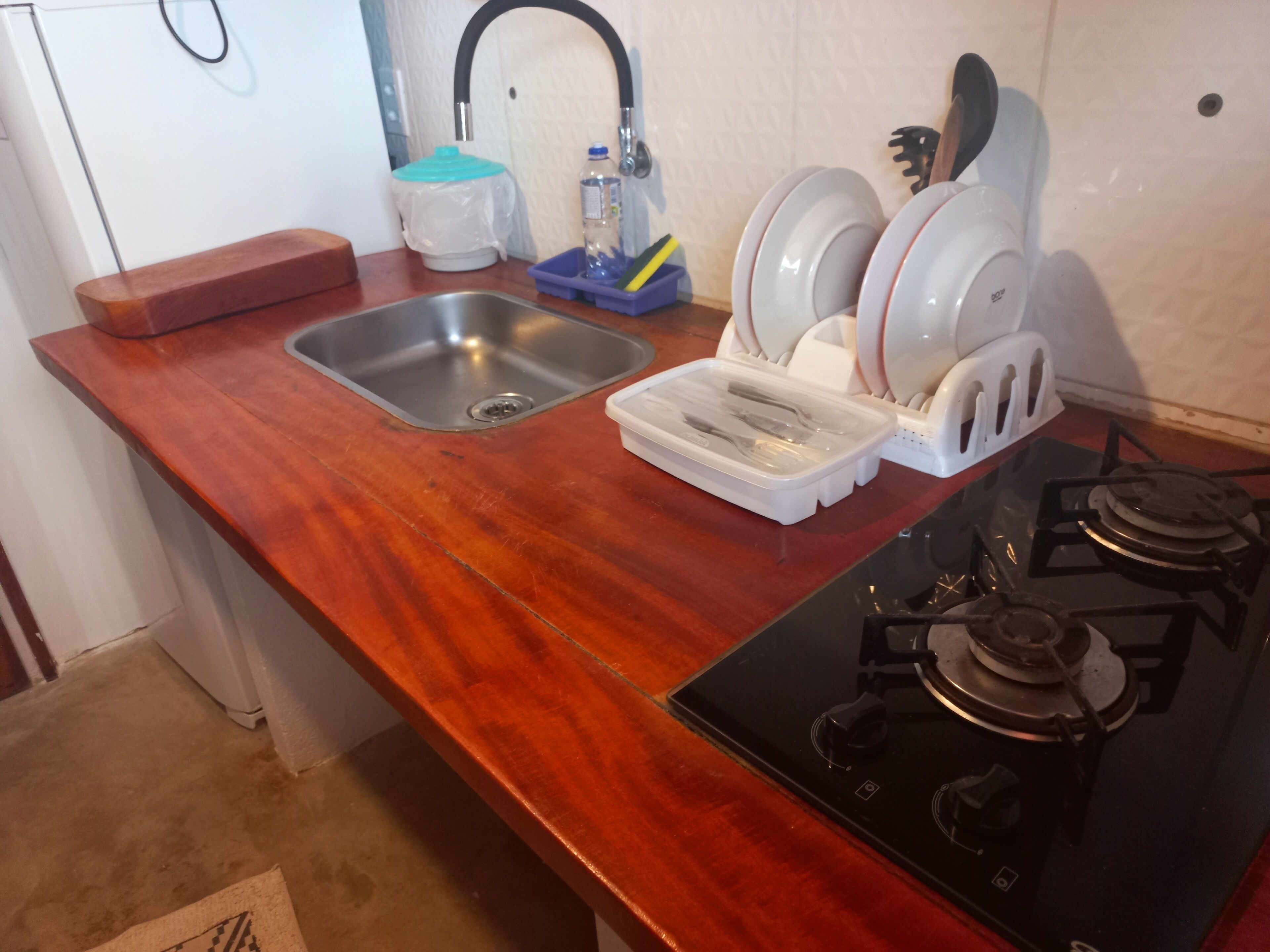 A kitchen with a stainless steel sink, a gas stove, and a dish drying rack.