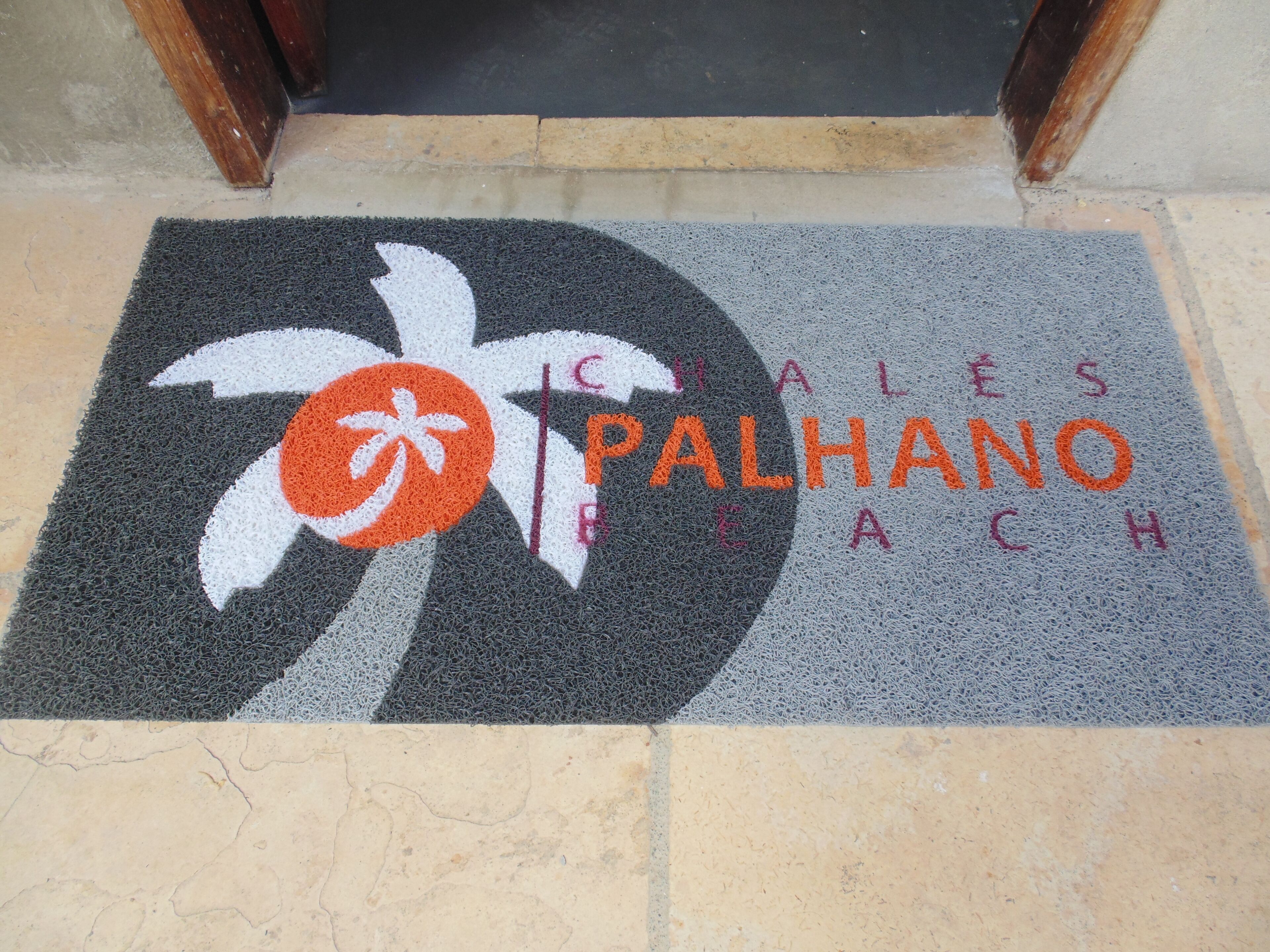 Un zerbino con una palma e la scritta "PALHANO BEACH" in arancione.